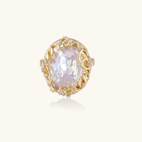 Gold filigree crown ring cradling an iridescent baroque freshwater pearl with crystal accents on white background