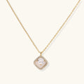 Gold quatrefoil pendant with crystal center on iridescent mother-of-pearl base, adjustable gold chain on cream background