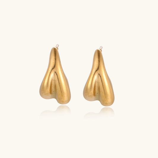 Pair of sculptural gold stud earrings with twisted organic forms on cream background